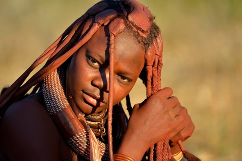 Young Himba woman doing her hair, Ombombo, Kaokoland, Kunene, Namibia, Africa