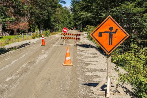 Construction work on the Carretera Austral road, stop sign, gravel road, forest north of Caleta