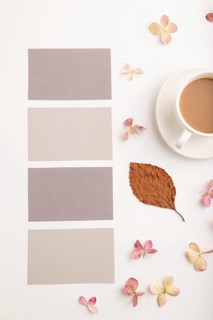 Composition with gray paper business card, brown beech autumn leaves, hydrangea flowers and cup of