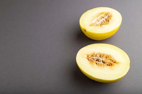 Sliced ripe yellow melon on gray pastel background. Side view, copy space. harvest, women health,