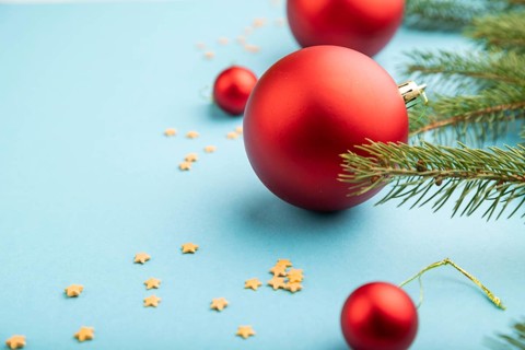 Christmas or New Year composition. Decorations, red balls, fir and spruce branches, on a blue paper