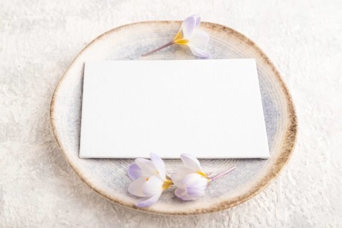 White paper invitation card, mockup with crocus flowers on ceramic plate and gray concrete