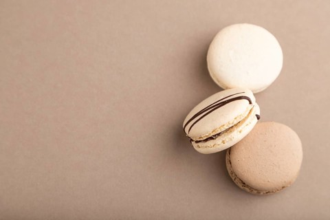 Brown and white macaroons on beige pastel background. top view, flat lay, copy space, still life.