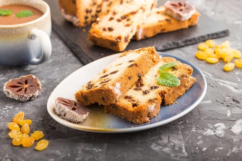 Homemade cake with raisins, dried persimmon and a cup of hot chocolate on a black concrete