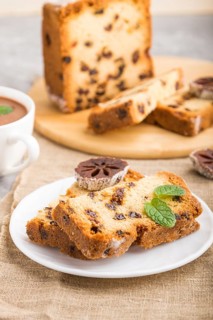 Homemade cake with raisins, dried persimmon and a cup of hot chocolate on a gray concrete