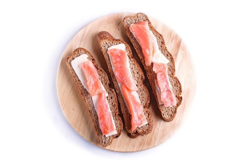 Smoked salmon sandwiches with butter on wooden board, isolated on white background. close up