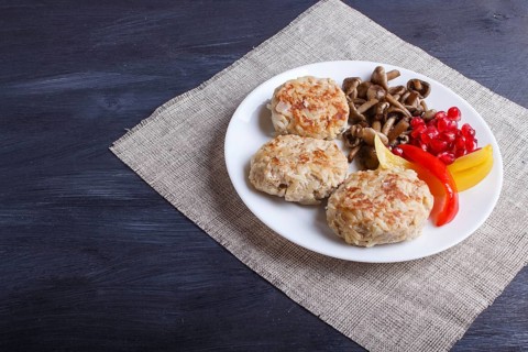 Meatballs with rice mushrooms, sweet peppers and pomegranate seeds on black wooden background.