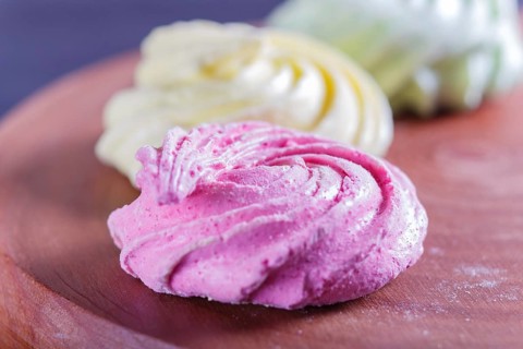 Colored meringues on wooden board, selective focus, close up