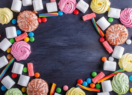 Colorful frame of multicolored candies on black wooden background. Circle copy space, top view,