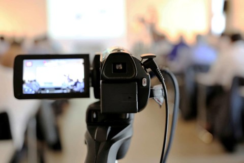 Close-up of a camcorder at a conference or press conference. The guests can be recognised out of