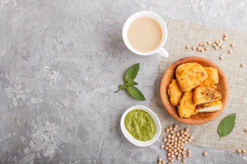 Traditional indian food paneer pakora in wooden plate with mint chutney on a gray concrete