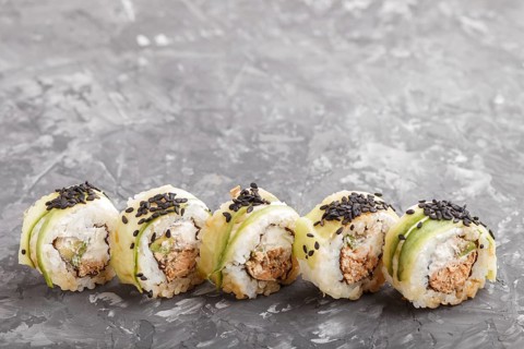 Japanese maki sushi rolls with tuna, cucumber, black sesame, cheese on black concrete background.