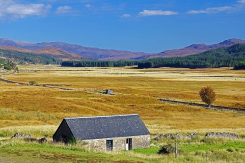 Small stone house on a wide, grassy plain under a clear blue sky, autumn, October, Highlands,