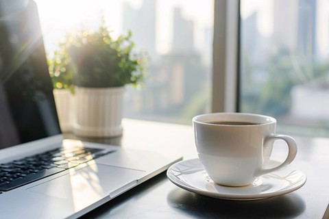 Cup of coffee on table next to laptop. KI generiert, generiert, AI generated