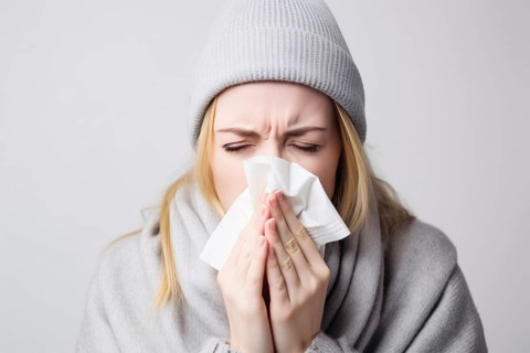 Young woman with cold sneezing into paper tissue. KI generiert, generiert AI generated