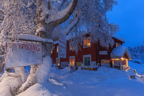 Illuminated Swedish red wooden house, shop, snow, twilight, winter, Porjus, Lapland, Sweden, Europe