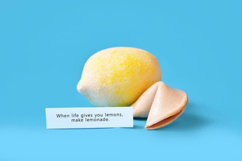 Fortune cookie with motivational text on paper saying 'When life gives you lemons, make lemonade'