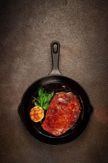 Grilled rib eye steak, in a cast-iron skillet, top view, homemade, no people