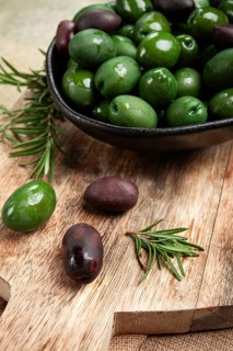 Chalkidiki olives, classic Greek green olives, in a bowl on a cutting board, top view, without