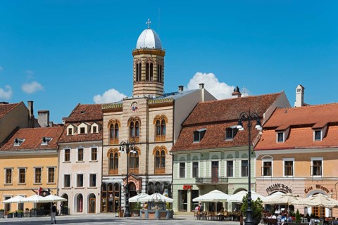 Historic city centre with colourful buildings and a café under a clear blue sky, Church of the