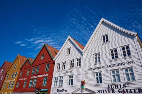 Traditional wooden houses under a blue sky with pitched roofs and multiple windows in a sunny old