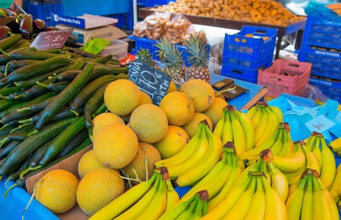 Market stall with a variety of fresh fruit such as bananas, melons and cucumbers. A colourful and