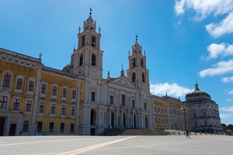 Monumental baroque architecture with two towers and detailed façade under a clear sky, National