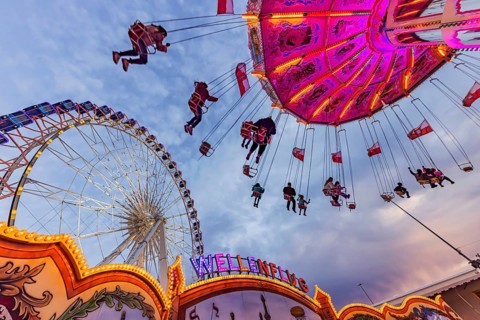 Chain carousel and Ferris wheel in the evening. 177th Cannstatter Volksfest at the Cannstatter