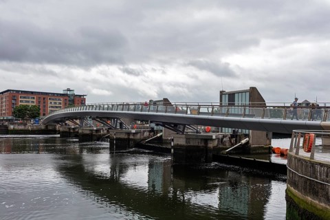 Modern designed bridge spanning a river under a cloudy sky, Belfast