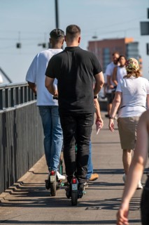 Pedestrians and e-scooters on a pavement, getting close and in each other's way, illegal driving on