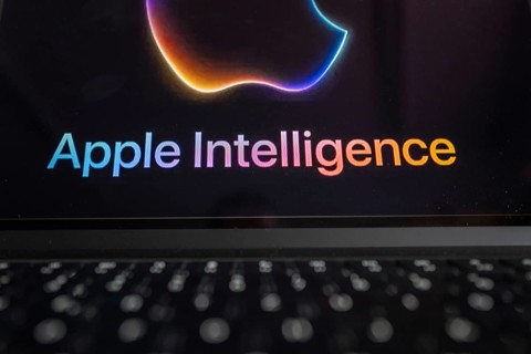 Apple logo in bright neon colours on a Macbook with illuminated keyboard and the text 'Apple