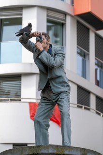 Real crow on a pillar saint, The Photographer, in front of the main railway station in Düsseldorf,