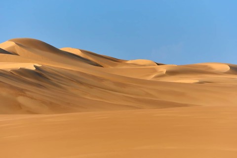Sand dunes under a blue sky, conveying a calm and vast desert landscape, Matruh, Great Sand Sea,