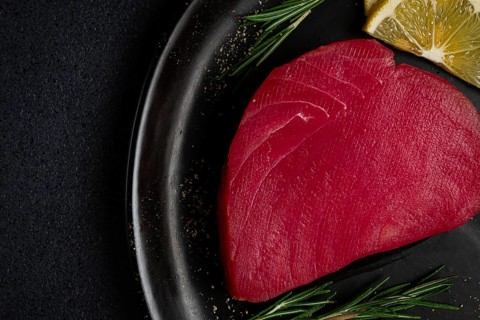 Fresh red tuna fillet, for steak, raw, top view, on a black plate, no people