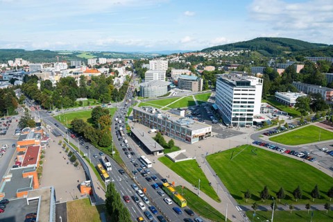 View of an urban neighbourhood with busy traffic, large green areas and surrounding mountain