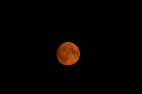 Full super moon red orange in colour in the night sky, Suffolk, England, United Kingdom, Europe