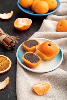 Truffle chocolate tangerine candies on a black concrete background and linen textile. Side view,