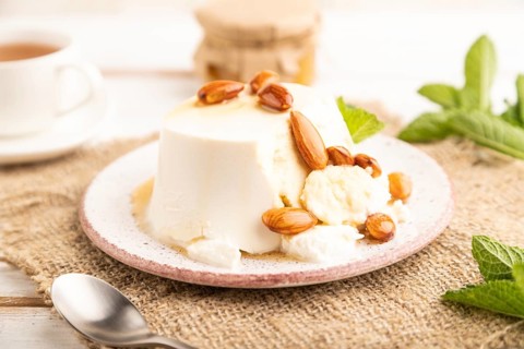 Ricotta cheese with honey and almonds on white wooden background and linen textile. side view,