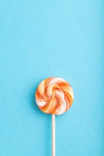 Single lollipop candy on blue pastel background. copy space, top view, flat lay