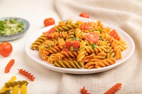 Tortiglioni semolina pasta with tomato and microgreen sprouts on a white wooden background and