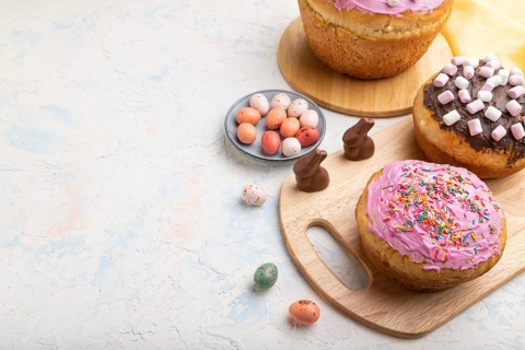 Homemade glazed and decorated easter pies with chocolate eggs and rabbits on a white concrete