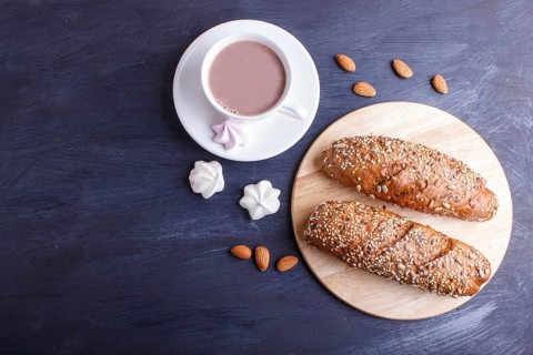 Rye bread with sunflower seeds, sesame and flax with cup of cocoa on dark blue background. top