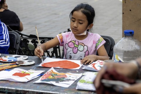 Oaxaca, Mexico, Students painting at a temporary art class in the zocalo. A girl paints a heart the