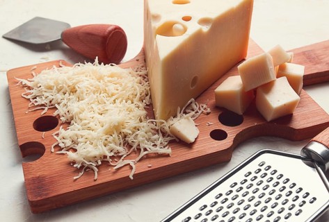 Grated cheese, Maasdam, on a cutting board, grater and cheese knife, close-up, no people