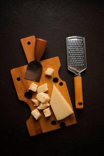 Hard cheese, parmesan, on a cutting board, cheese knife, grater, top view, no people