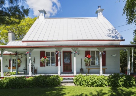 Old circa 1840 white horizontal wood plank with red trim Canadiana style house facade with silver