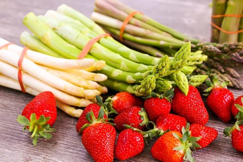 Green asparagus, white asparagus and fresh strawberries decorated on a rustic wooden table