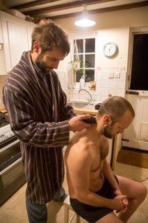 Young man shaving his brother's head home haircut in kitchen, UK, model released