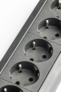 Part of a black plastic socket strip with empty sockets