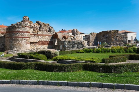 Ancient ruins under a clear blue sky with visitors exploring the historic site, Western Fortress